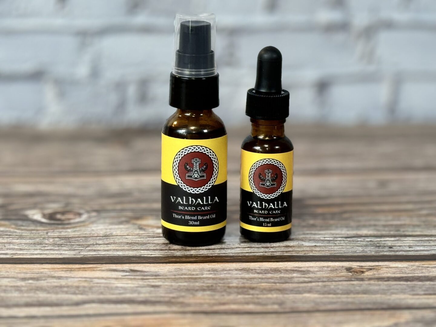 Two bottles of oil sitting on top of a wooden table.